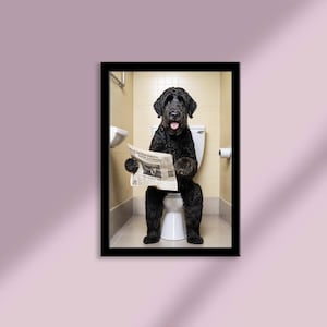 Peut inclure: Impression encadrée d'un chien noir assis sur des toilettes, lisant un journal. La langue du chien est sortie. La salle de bain comprend des toilettes blanches, un porte-papier toilette et un lavabo mural.