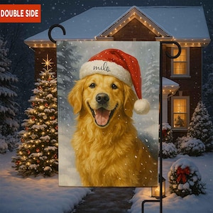 Puede incluir: Una bandera de jardín de doble cara con un Golden Retriever que lleva un gorro de Papá Noel con el nombre "milo". El perro sonríe en una escena invernal nevada con un árbol de Navidad y una casa al fondo.