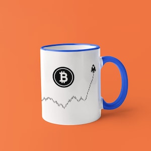 May include: White ceramic mug with a blue handle and rim. The mug features a black Bitcoin symbol and a rocket graphic on a rising stock chart. The background is orange.