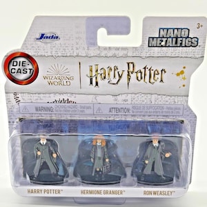 May include: A packaged set of three die-cast metal Harry Potter character figures. The figures include Harry Potter, Hermione Granger, and Ron Weasley. The packaging features the "Harry Potter" logo and "Nano Metalfigs" branding.