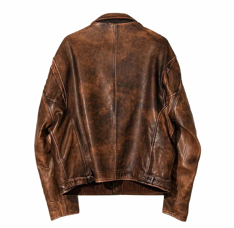 Puede incluir: Chaqueta de cuero marr&oacute;n con acabado envejecido. La chaqueta tiene cuello cl&aacute;sico, cierre de cremallera y cintur&oacute;n en la cintura. La chaqueta tiene un aspecto vintage.