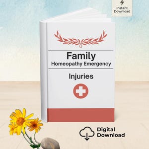 May include: A white book titled "Family Homeopathy Emergency Injuries" with a red cross symbol. The book has a red band at the bottom and a decorative floral design at the top. A sprig of yellow flowers and two stones are in the foreground.
