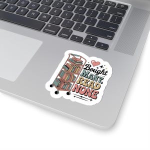 Op de afbeelding: Een gestanste sticker met een roze rolwagen vol kleurrijke boeken, een klein roze hartje en de tekst "Bought MANY, READ NONE" in een retro-geïnspireerd lettertype. De sticker is aangebracht op het oppervlak van een zilverkleurig laptoptoetsenbord.