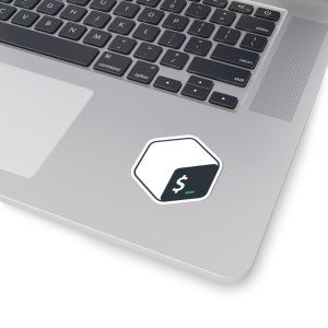 May include: A white and dark grey hexagonal sticker featuring a dollar sign icon and a green prompt line, placed on a laptop. The sticker has a black border and is on a silver laptop.