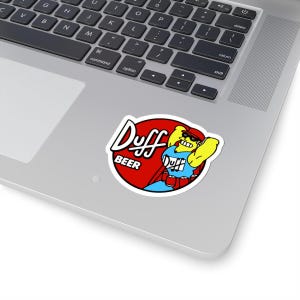 May include: A sticker with the "Duff Beer" logo. The design features a red circle with the words "Duff" and "BEER" in white. A cartoon character in a blue shirt, red cape, and sunglasses is flexing.