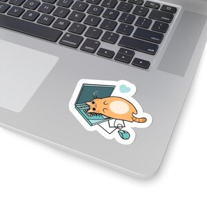 Op de afbeelding: Een sticker met een cartoon oranje kat die op een laptop ligt. Het laptopscherm toont een laadsymbool. Een blauw hart en een computermuis zijn ook afgebeeld. De sticker bevindt zich op een zilveren laptop.