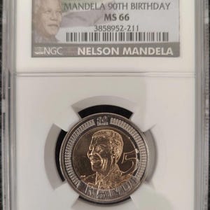 Op de afbeelding: Een Zuid-Afrikaanse 5 Rand munt uit 2008 ter herdenking van de 90e verjaardag van Nelson Mandela, beoordeeld als MS 66 door NGC. De munt toont een portret van Mandela, het cijfer 5 en de tekst 90 YEARS en RAND, verpakt in een doorzichtige houder.