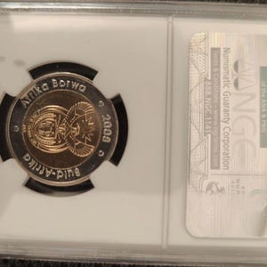 Op de afbeelding: Een Zuid-Afrikaanse munt uit 2009, ingesloten in een rechthoekige NGC beschermende plastic houder. De munt bevat de tekst Afrika Borwa en Suid-Afrika, met een centraal embleem dat een schild en een secretarisvogel weergeeft.