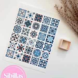 Puede incluir: Una hoja rectangular que presenta una cuadrícula de treinta y cinco azulejos cuadrados con intrincados patrones florales y geométricos en azul, rojo y blanco. Junto a la hoja hay un cortador de galletas cuadrado de plástico color melocotón claro.