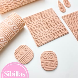 May include: A selection of light peach-coloured clay cutters and rolling pins featuring a Greek key design. The set includes two rolling pins, several square and oval cutters, and two teardrop-shaped cutters. The Sibillas Cutters logo is visible.