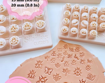 May include: Beige plastic Sibillas cutters sets featuring various insect and bug shapes in 10 mm (0.4 in), 15 mm (0.6 in), and 20 mm (0.8 in) sizes. A flat piece of light brown clay displays the impressed designs of butterflies, bees, snails, and beetles.