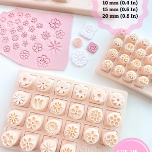 Pode incluir: Cortadores de argila de plástico rosa claro em forma de flor dispostos em grades em bandejas retangulares. Uma folha de argila rosa mostra padrões florais impressos. O texto diz: 3 sizes: 10 mm, 15 mm, 20 mm e Sibillas cutters.