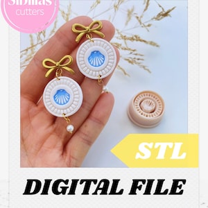 Puede incluir: Pendientes redondos de concha marina blancos y azules con detalles de lazo dorado y una gota de perla. Los pendientes tienen un diseño de concha en el centro. La imagen también incluye un cortador rosa y el texto "DIGITAL FILE".