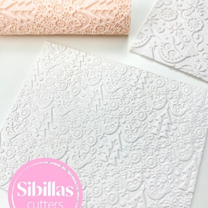 May include: Image of baking tools, featuring textured rolling pins and patterned fondant sheets. The rolling pins are a light peach colour, and the fondant sheets are white. The image includes the text "Sibillas cutters" in a pink circle.