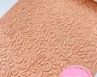 May include: A terracotta-colored, textured rolling pin and a sheet of fondant with an embossed floral design. The rolling pin is white with a matching floral pattern. The pink circle with the text "Sibillas cutters" is in the lower right corner.