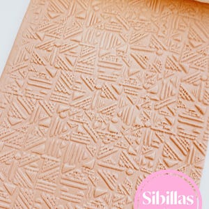 May include: A light peach-colored rectangular texture sheet featuring a repeating geometric pattern of triangles, lines, and small circles. A white rolling pin is visible at the top. A pink circular logo with the text Sibillas cutters is present.