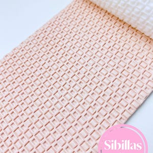 Può includere: Un mattarello rosa chiaro strutturato e un foglio abbinato con un motivo a cialda. Il mattarello è bianco. L'immagine include un cerchio rosa con il testo "Sibillas cutters".