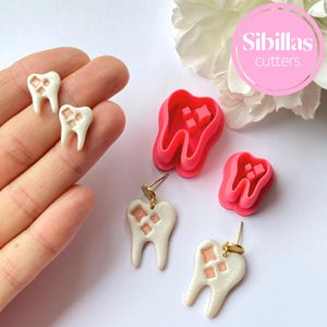 May include: White tooth-shaped earrings with gold posts and pink details, and two matching cutters. The earrings and cutters have a pearlescent finish. The image also includes the text "Sibillas cutters" in a pink circle.