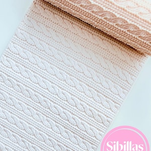 Pode incluir: Um tapete de impressão de silicone retangular com um padrão de textura de malha de cabo em relevo. O tapete transita de uma cor pêssego clara no topo para uma cor branca na parte inferior. Um logótipo circular rosa com o texto Sibillas cutters é visível.