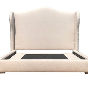 May include: A beige upholstered bed frame with a tall, arched headboard and tufted details. The headboard has a wingback design with nailhead trim.