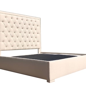 May include: A tufted upholstered bed frame with a tall headboard and a beige fabric covering. The bed frame has a storage compartment underneath.