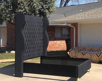 May include: A black upholstered headboard with a tufted design and a matching black bed frame. The headboard is tall and has a curved top. The bed frame is low to the ground and has a simple design.