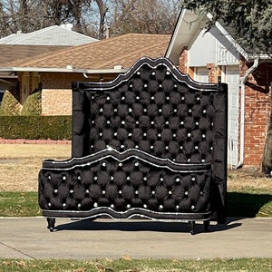 Puede incluir: Un cabecero tapizado en terciopelo negro con ribete plateado y detalles de cristal. El cabecero es alto y tiene una parte superior curvada.