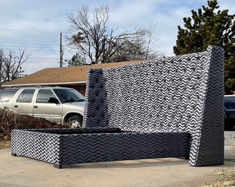 May include: A gray tufted headboard with a wavy pattern and a matching footboard. The headboard is tall and the footboard is low. The bed frame is in a driveway.