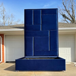 Puede incluir: Una cabecera tapizada de color azul marino con un diseño geométrico. La cabecera está unida a un somier de plataforma azul marino a juego.