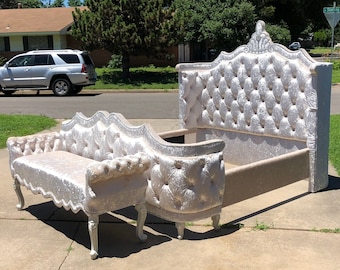 May include: A white tufted headboard with a matching tufted bench. The headboard has a decorative crown design and the bench has a curved back and legs.