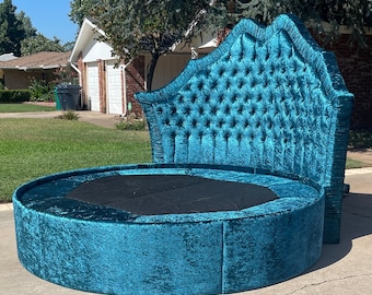 May include: A teal blue round bed with a tufted headboard. The headboard has a unique design with a scalloped top and a button tufted pattern.