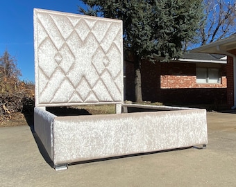 Puede incluir: Una estructura de cama tapizada en blanco con una cabecera capitoné. La cabecera tiene un patrón de diamante y el marco tiene un diseño rectangular simple.