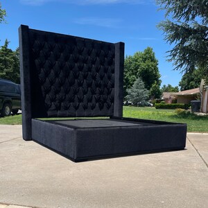 May include: A black upholstered bed frame with a tall tufted headboard. The headboard has a diamond pattern and the frame has a simple, rectangular design.