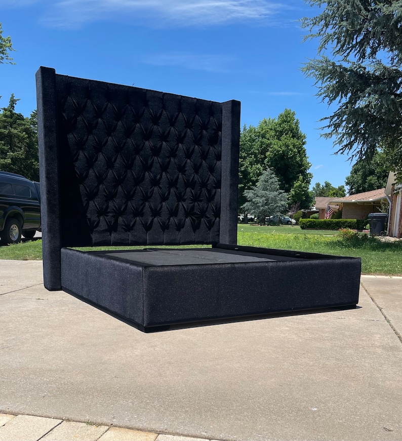 May include: A black upholstered bed frame with a tall tufted headboard. The headboard has a diamond pattern and the frame has a simple, rectangular design.