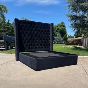 May include: A black upholstered bed frame with a tall headboard featuring a tufted design. The headboard is tall and has a square shape.