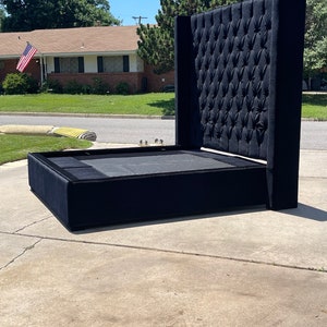 May include: A black upholstered bed frame with a tall, tufted headboard. The headboard has a diamond pattern and is very tall.