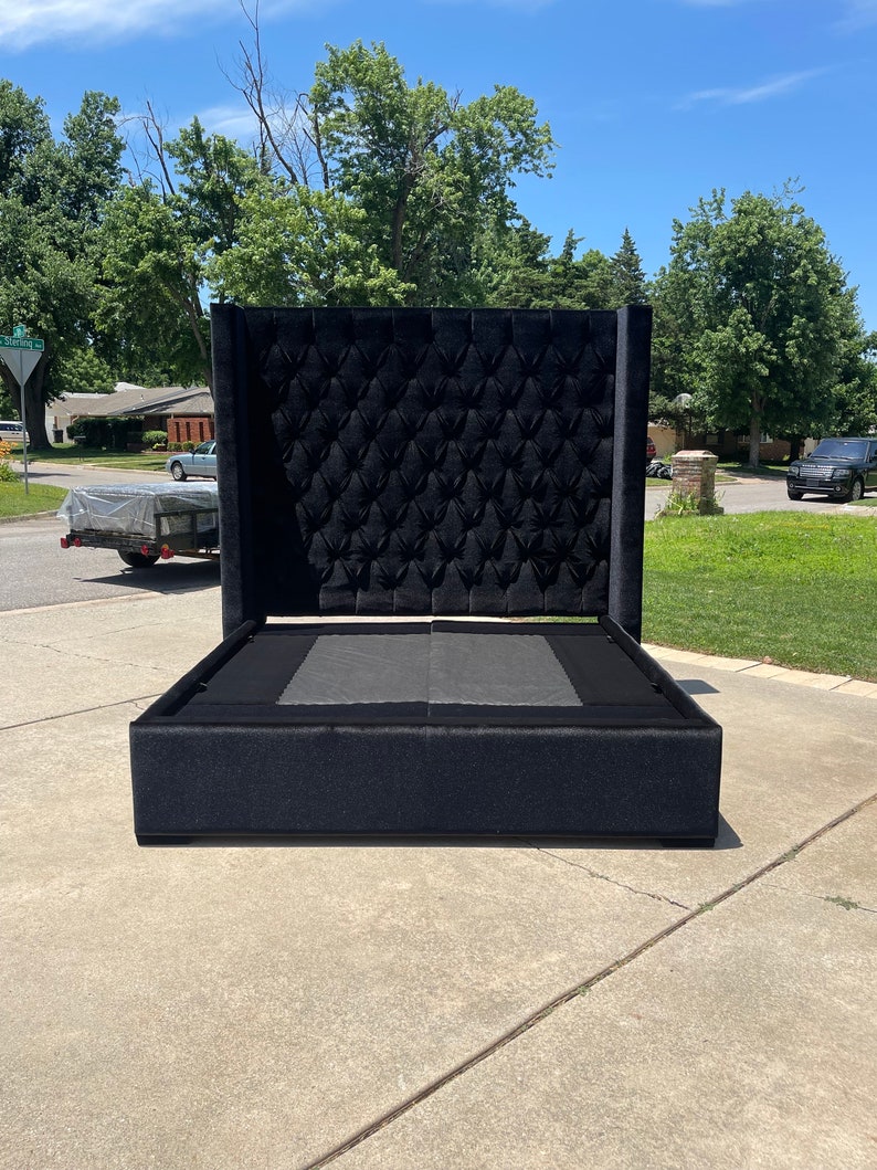 May include: A black upholstered bed frame with a tall headboard featuring a tufted design. The headboard is made of a soft, plush fabric.