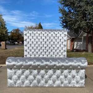 Puede incluir: Una cabecera y un piecero tapizados en plata con un patr&oacute;n de diamante. La cabecera es alta y el piecero es bajo. La cabecera y el piecero est&aacute;n tapizados en un terciopelo suave y mullido.