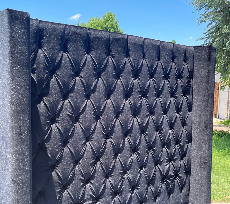 May include: A black tufted headboard with a diamond pattern. The headboard is made of a soft, plush fabric.