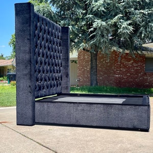 May include: A black upholstered bed frame with a tall tufted headboard. The headboard has a diamond pattern and is covered in a soft, plush fabric.