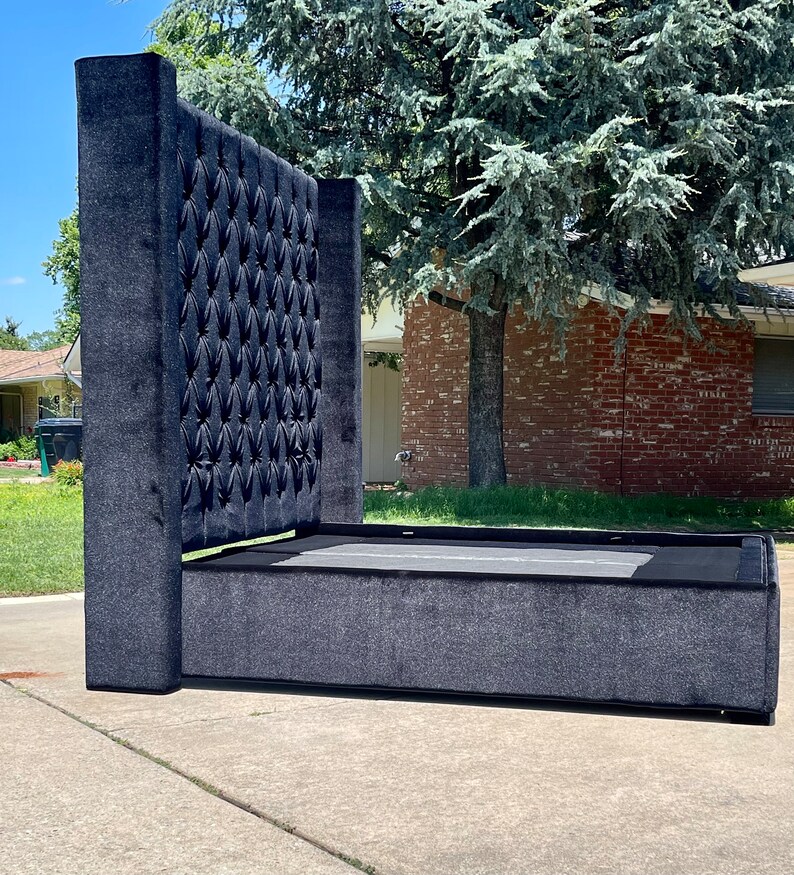 May include: A black upholstered bed frame with a tall tufted headboard. The headboard has a diamond pattern and is covered in a soft, plush fabric.