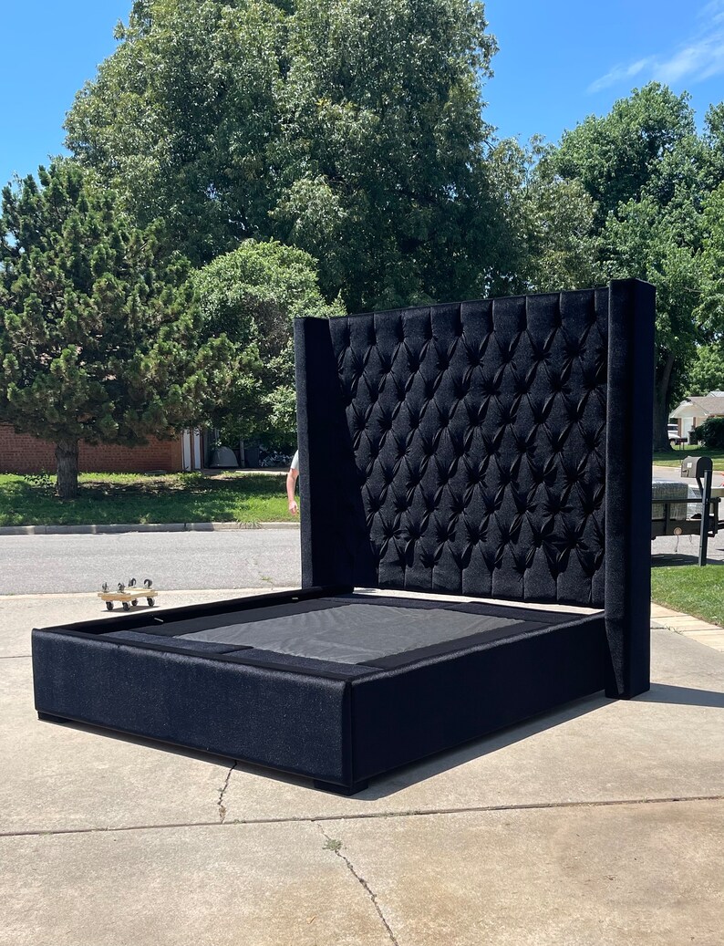 May include: A black upholstered bed frame with a tall headboard featuring a tufted design. The headboard is tall and has a square shape.