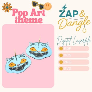 Peut inclure: Boucles d'oreilles en forme de chat bleu clair avec des yeux orange et un sourire édenté. L'image présente le thème "Pop Art" et "ZAP & Dangle". Les options de type de fichier sont : PDF, XCS, PNG et SVG.