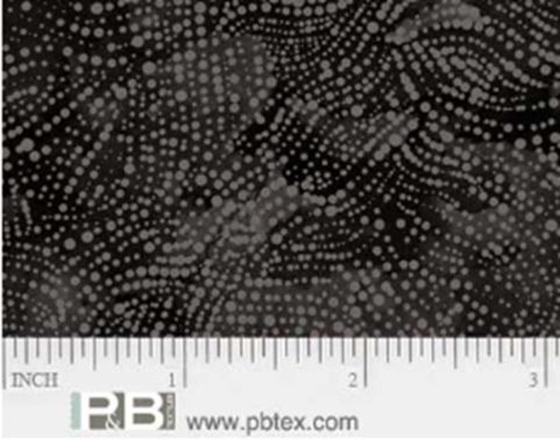 K&ouml;nnte beinhalten: Schwarzer Stoff mit einem wei&szlig;en Tupfenmuster. Die Punkte sind in einem wirbelnden, wellenf&ouml;rmigen Design angeordnet. Ein Lineal ist zur Skalierung enthalten und zeigt, dass der Stoff 7,6 cm breit ist.