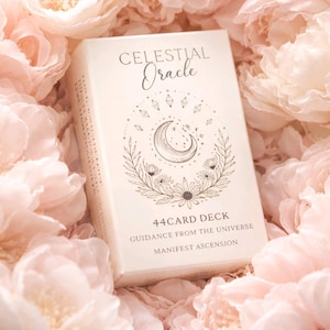 May include: A white card deck titled "Celestial Oracle" with a crescent moon and floral design. The box reads "44 Card Deck, Guidance from the Universe, Manifest Ascension." The deck is surrounded by soft pink flowers.