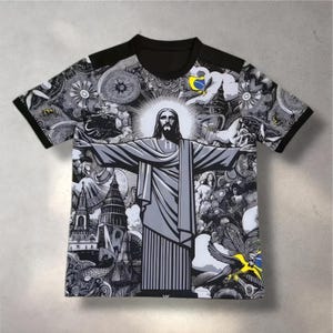 Könnte beinhalten: Schwarz-graues T-Shirt mit einer Grafik von Christus dem Erlöser. Das Design umfasst einen schwarzen Kragen und Ärmel, und das Bild enthält komplizierte Details und Muster in einer Graustufenpalette.