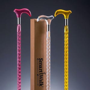 Puede incluir: Tres bastones de paseo coloridos, rosa, transparente y amarillo, con un patrón de corte de diamante. Cada bastón tiene un mango curvo y un eje plateado. Una caja marrón con el texto "SmartWalk" está detrás de los bastones.