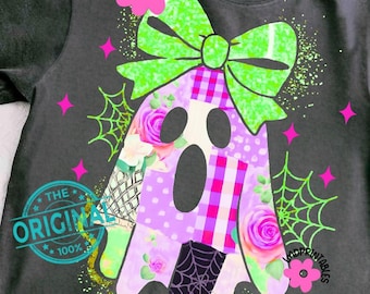 Può includere: T-shirt grigio scuro con un design a fantasma patchwork, un fiocco verde, fiori rosa e ragnatele. Il fantasma ha un motivo floreale e a pois. Il testo "THE ORIGINAL 100%" è stampato sulla maglietta.