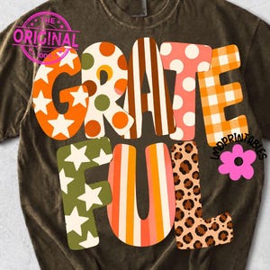 May include: A dark brown short-sleeve t-shirt featuring the word GRATEFUL in large, multi-patterned letters. The letters include orange stars, green polka dots, brown stripes, pink polka dots, orange gingham, green stars, and leopard print.