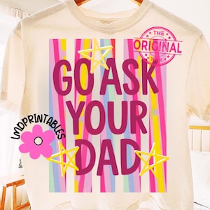 Puede incluir: Camiseta color crema con el texto rosa "GO ASK YOUR DAD" sobre un fondo de rayas verticales multicolores. La camiseta presenta estrellas y un sello rosa que dice "THE ORIGINAL 1984".